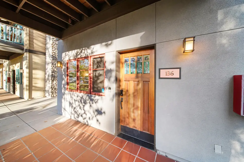 Covered entry with a wood front door and the number 136
