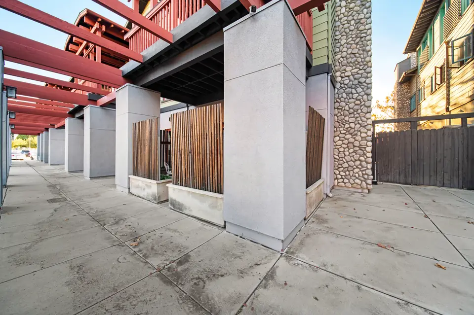 Walkway along the side of the building under red pergola beams